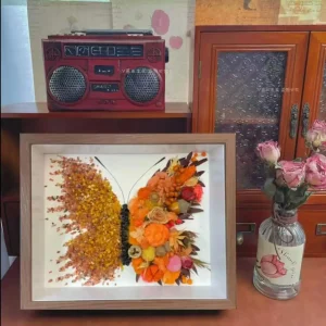 Close-up of flame orange crystals and pressed flowers in butterfly shadow box