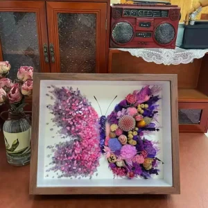 Close-up of pink Peach crystals and pressed flowers in butterfly shadow box
