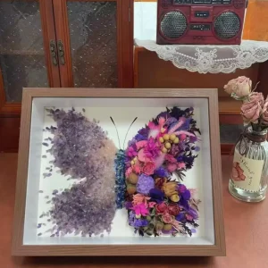 Close-up of purple peach crystals and pressed flowers in butterfly shadow box